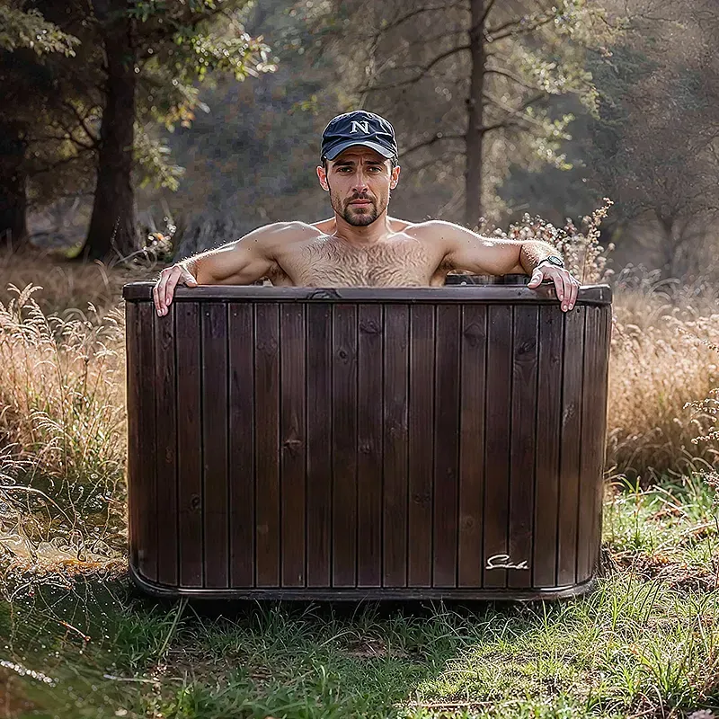 Un homme torse nu prend un bain dans une spa en bois.