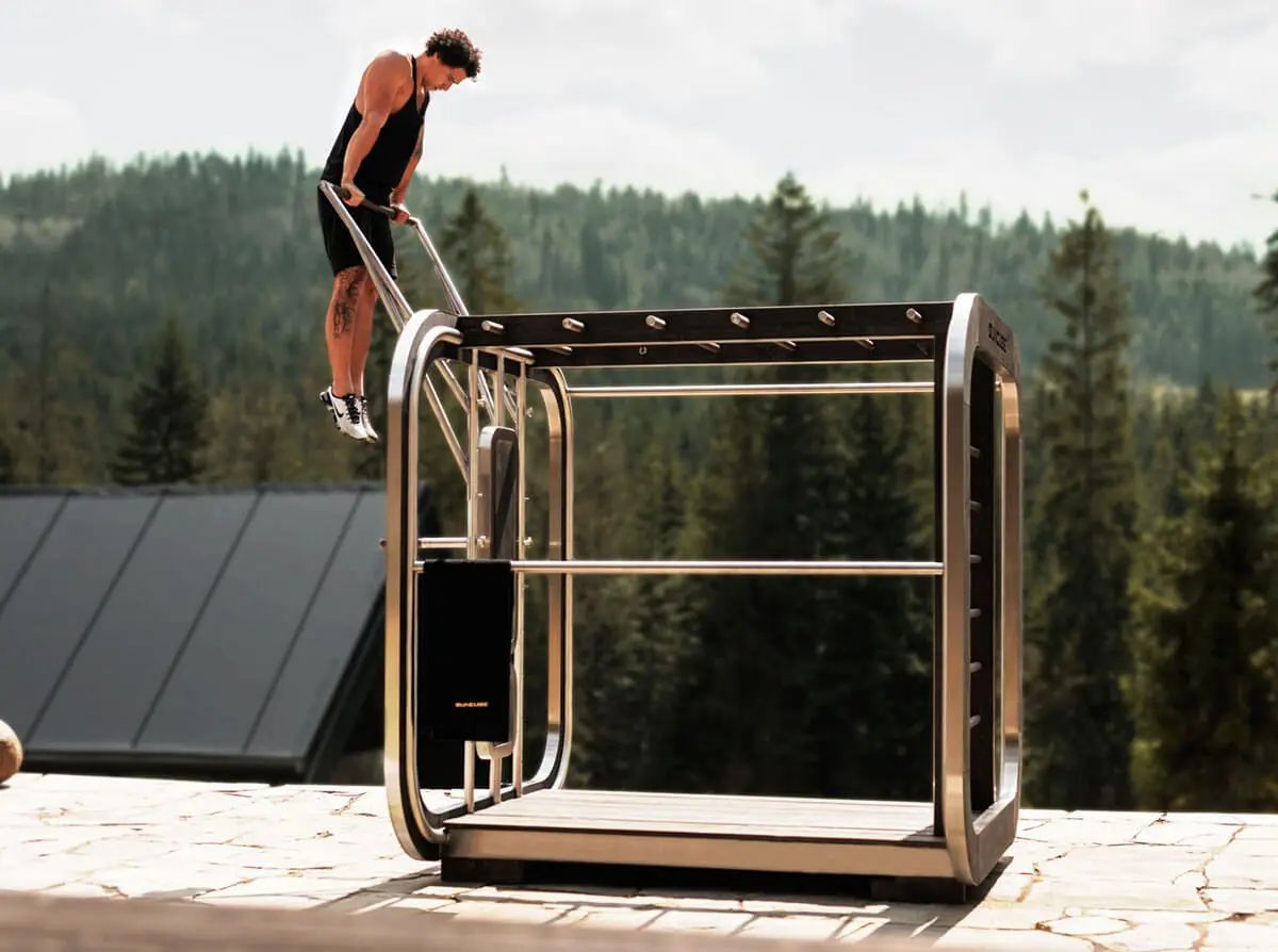 Un homme fait du sport sur une structure métallique Gymcube.