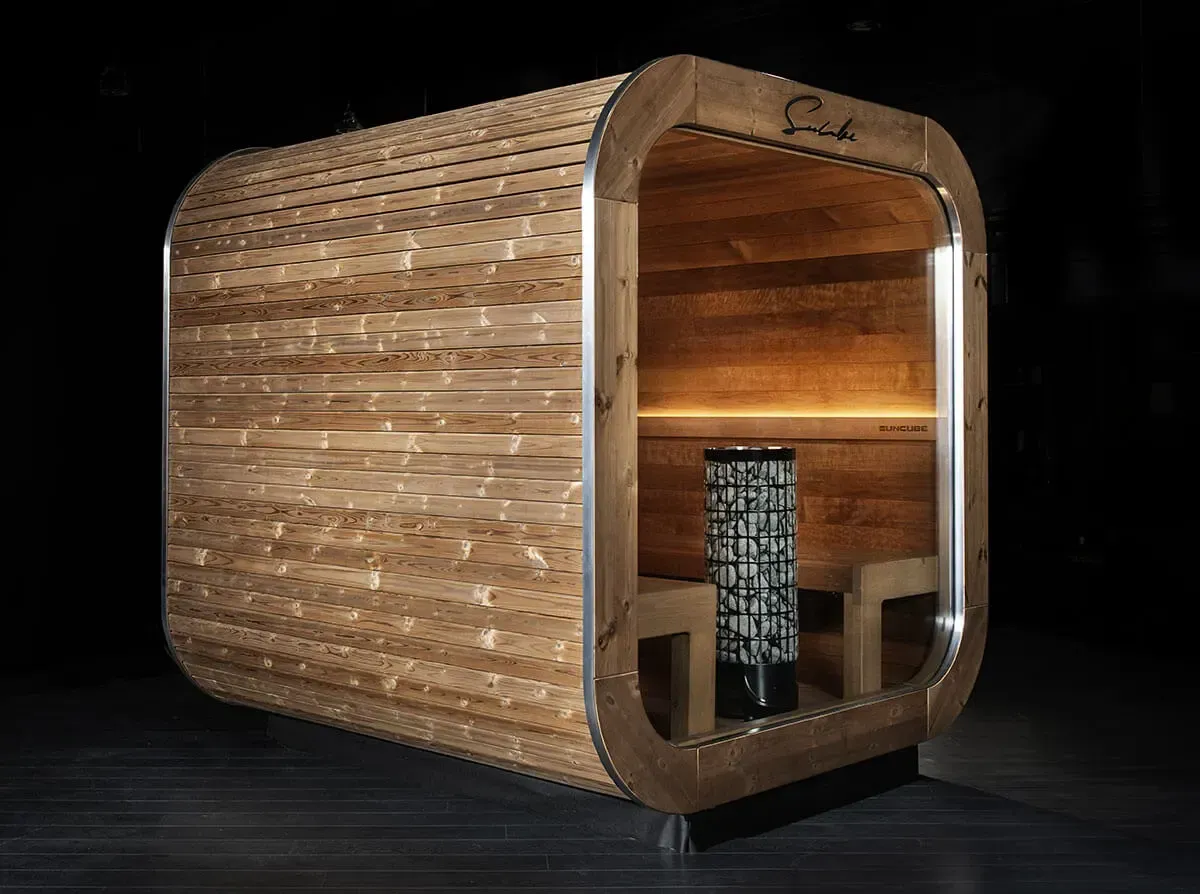 Un sauna en bois avec une porte vitrée est posé sur un plancher en bois.