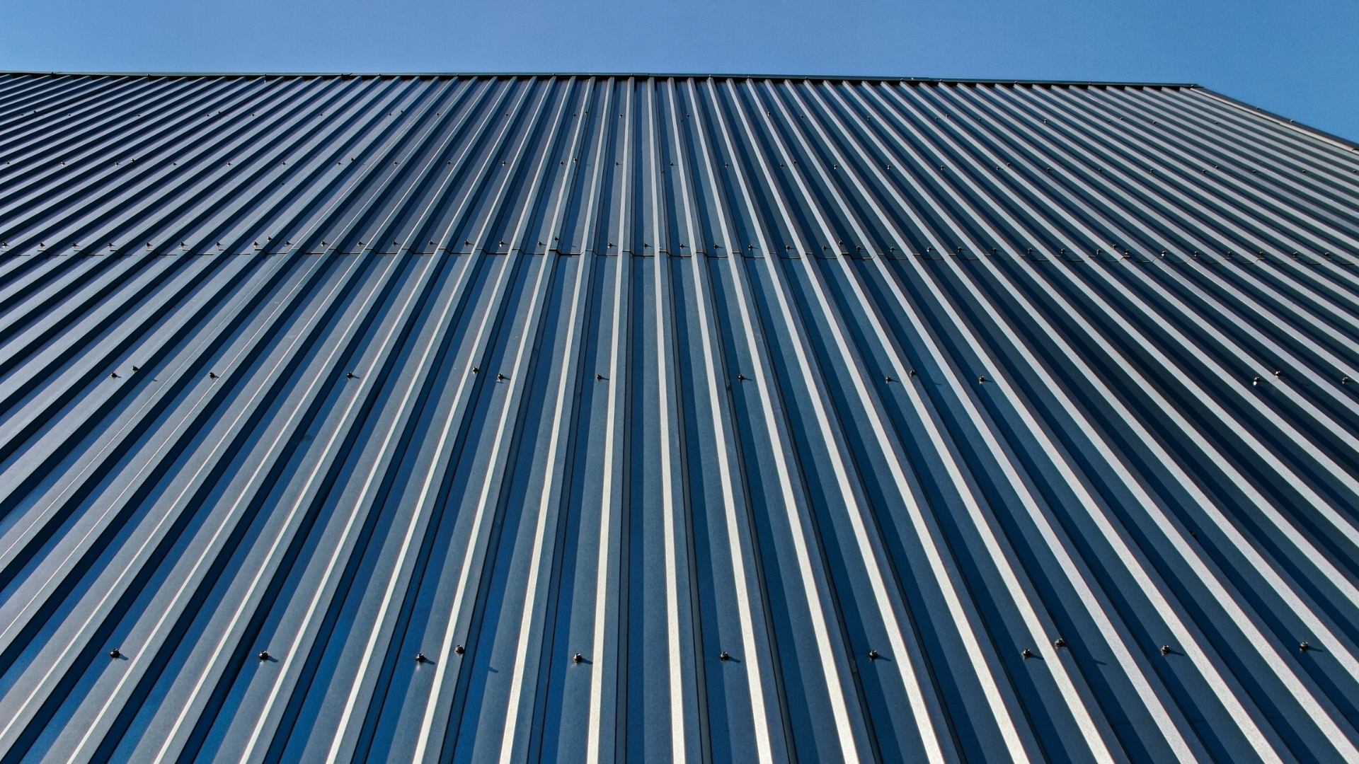 A close up of a metal roof with a blue sky in the background