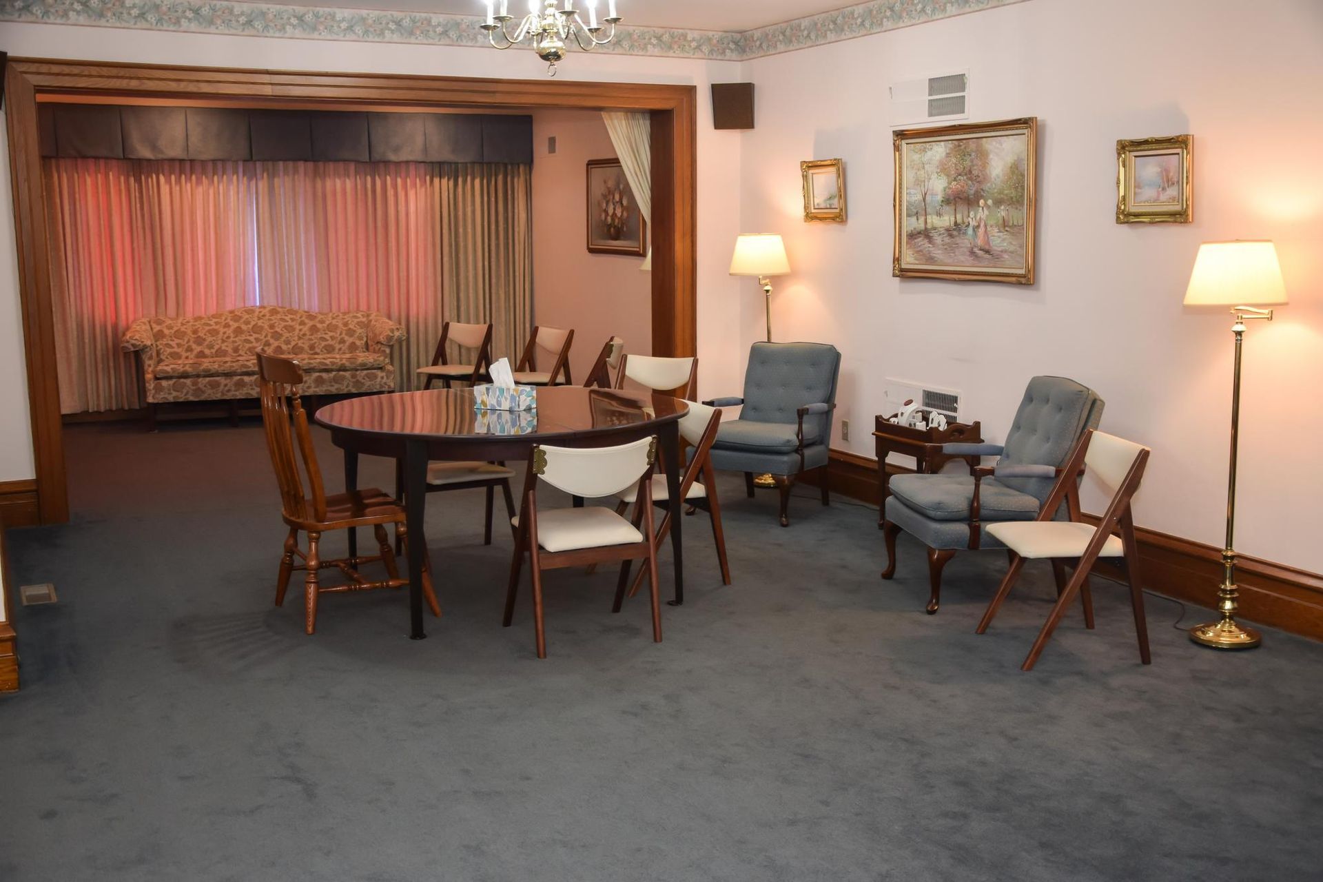Empty hotel lounge with round table, chairs, sofa, lamps, and blue carpet