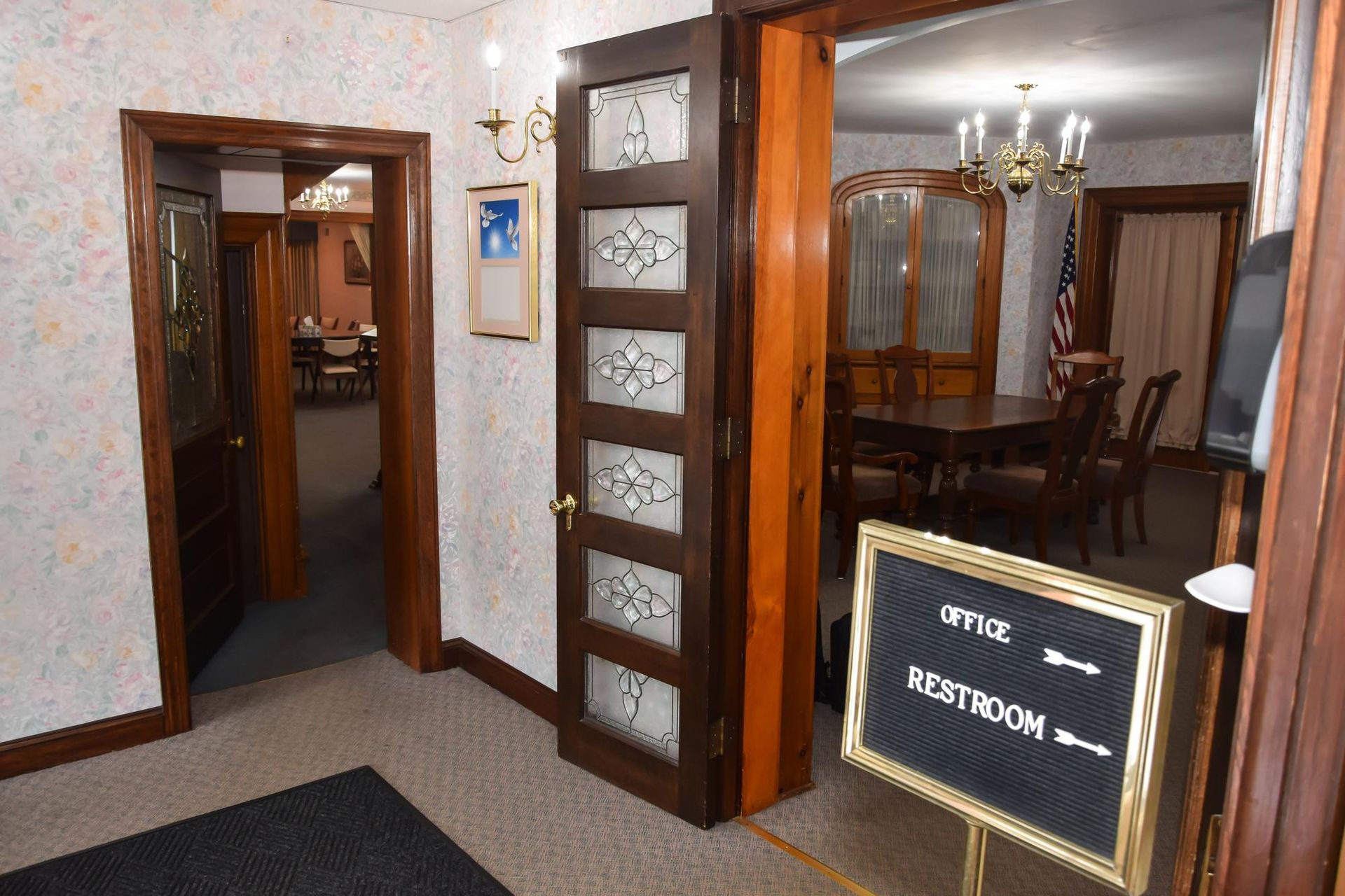 Wood-paneled corridor leading to a vestibule room with a chandelier and a sign reading “VESTIBULM”￼
