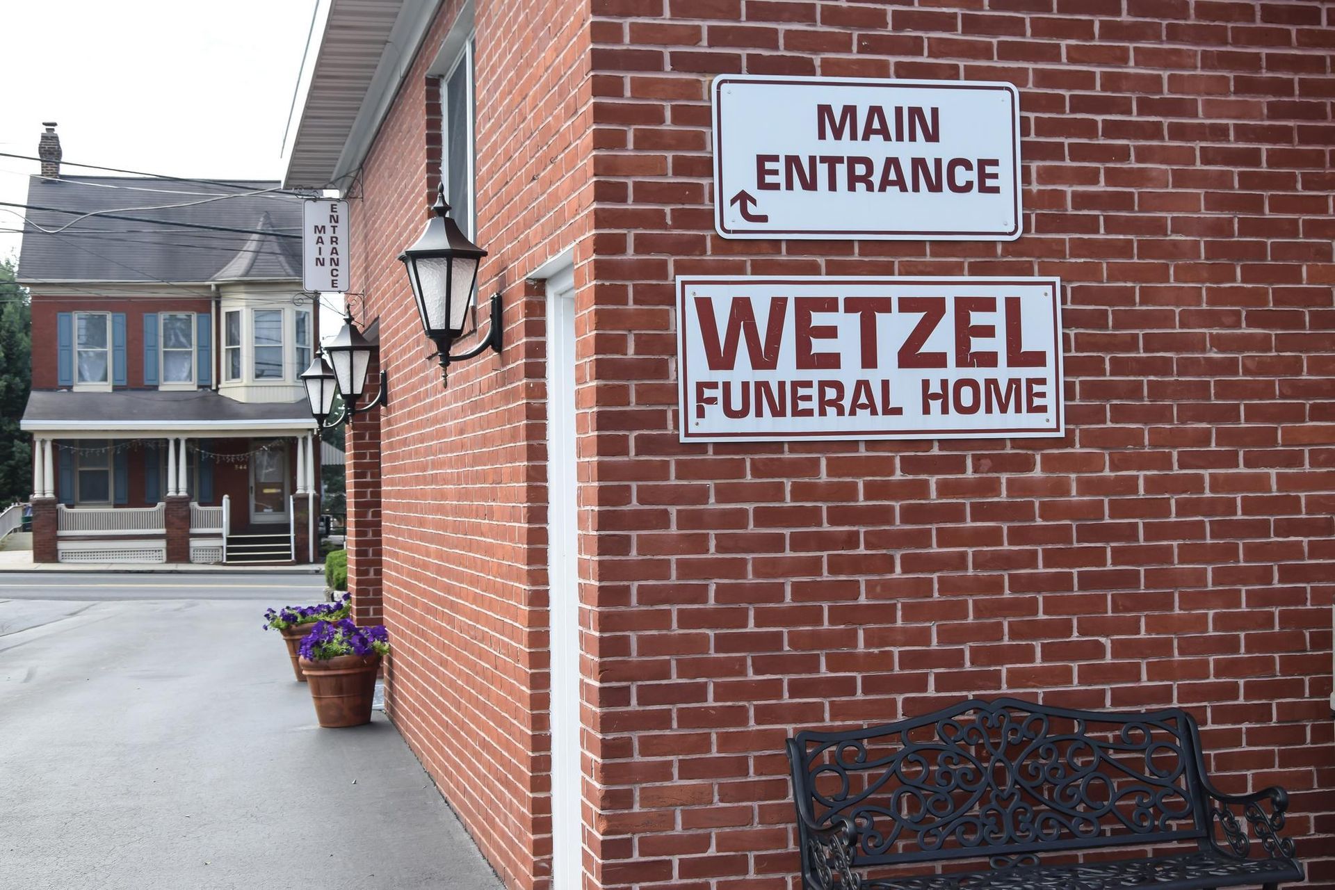 Wetzel Funeral Home brick building with main entrance sign and flower planter