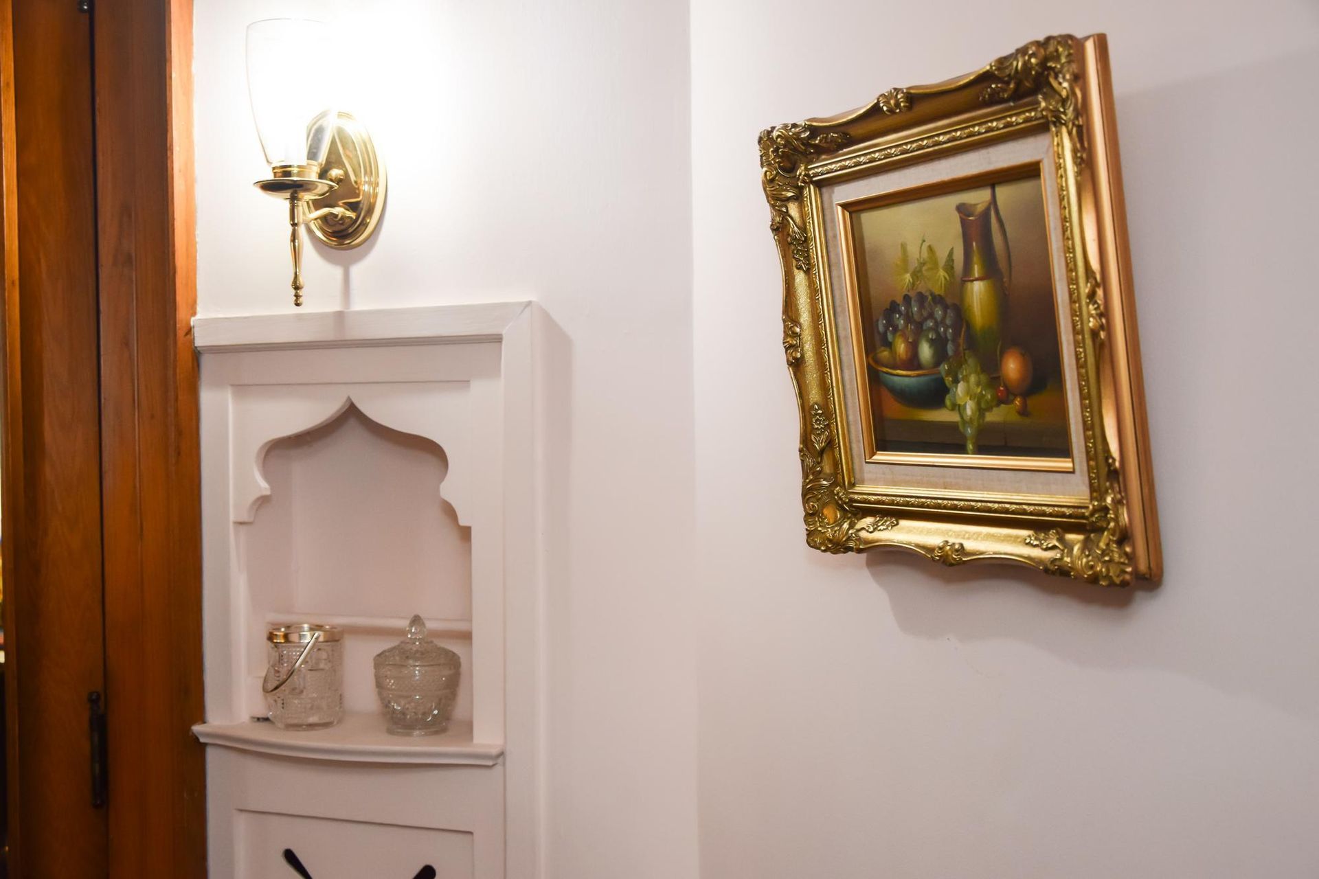 Hallway with a white niche shelf and a gold-framed floral painting on a cream wall