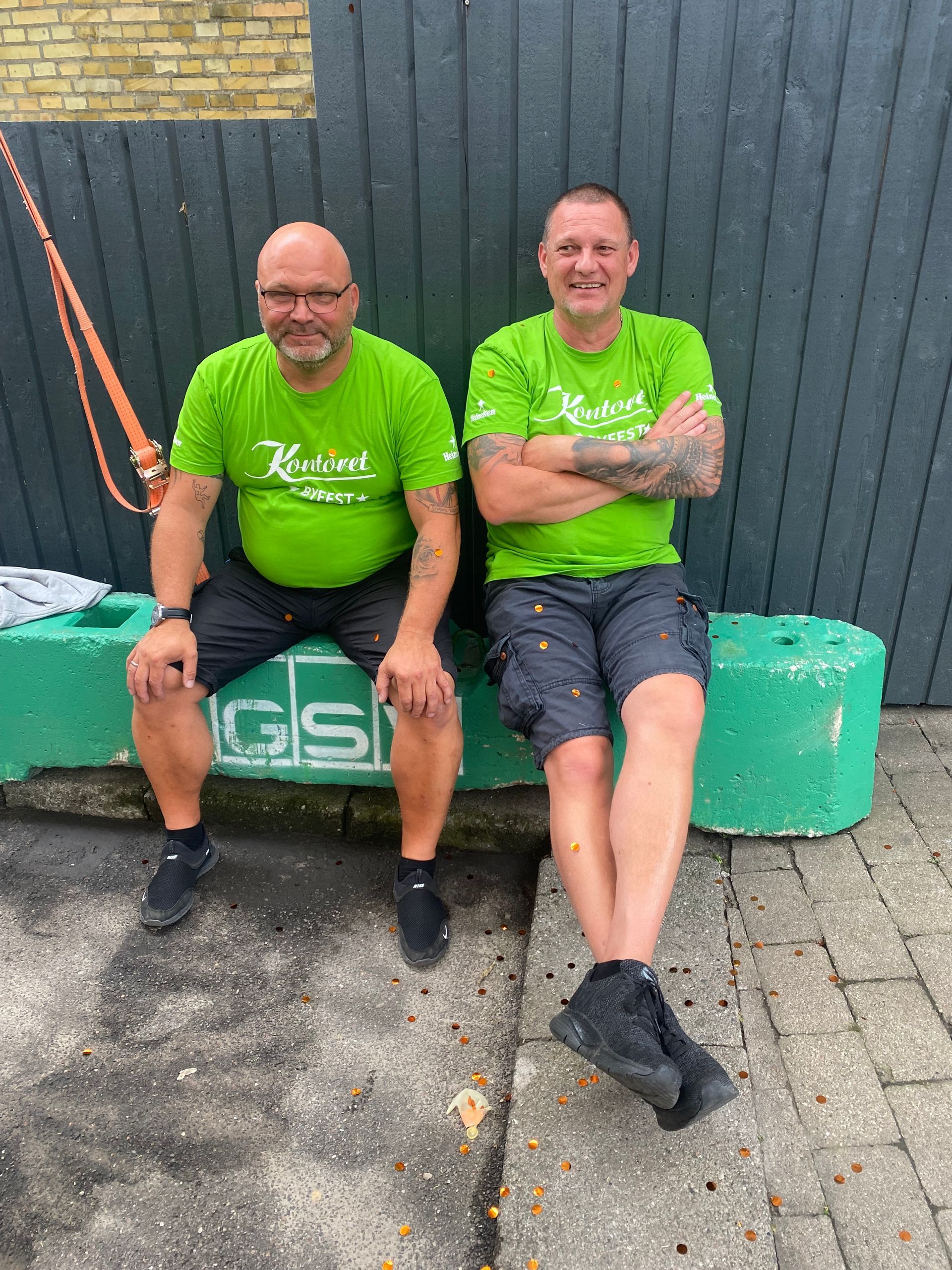 To mænd i grønne skjorter sidder på en grøn blok.