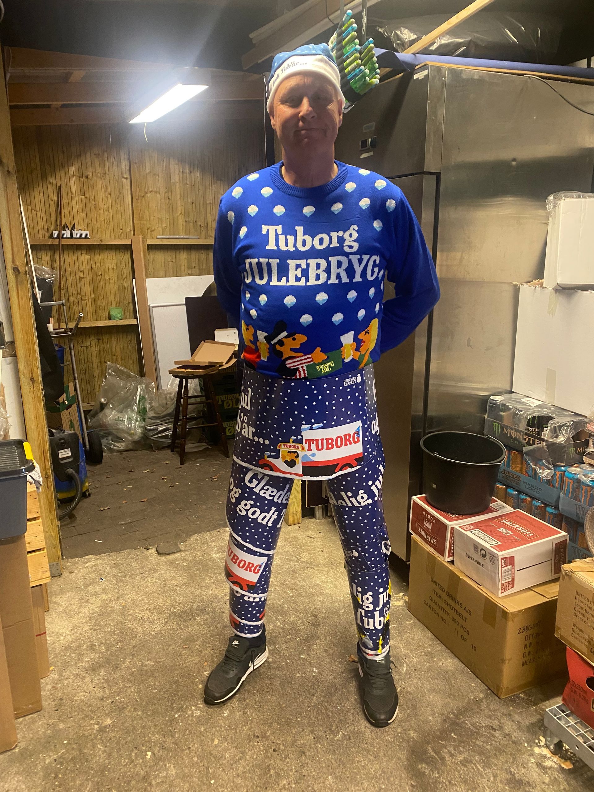 En mand iført en tuborg julebryg julesweater står i en garage.