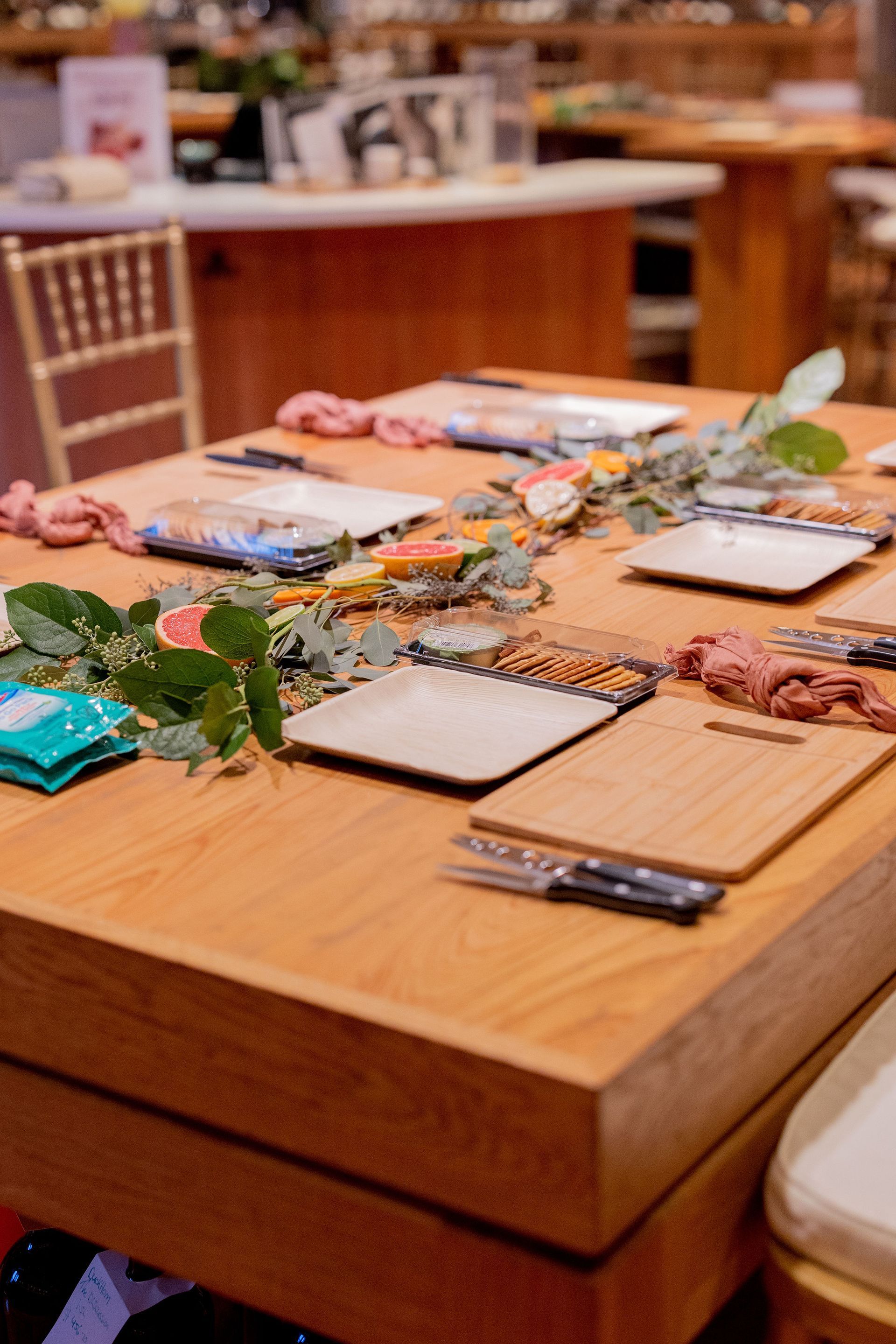 A wooden table with plates , knives , and napkins on it.