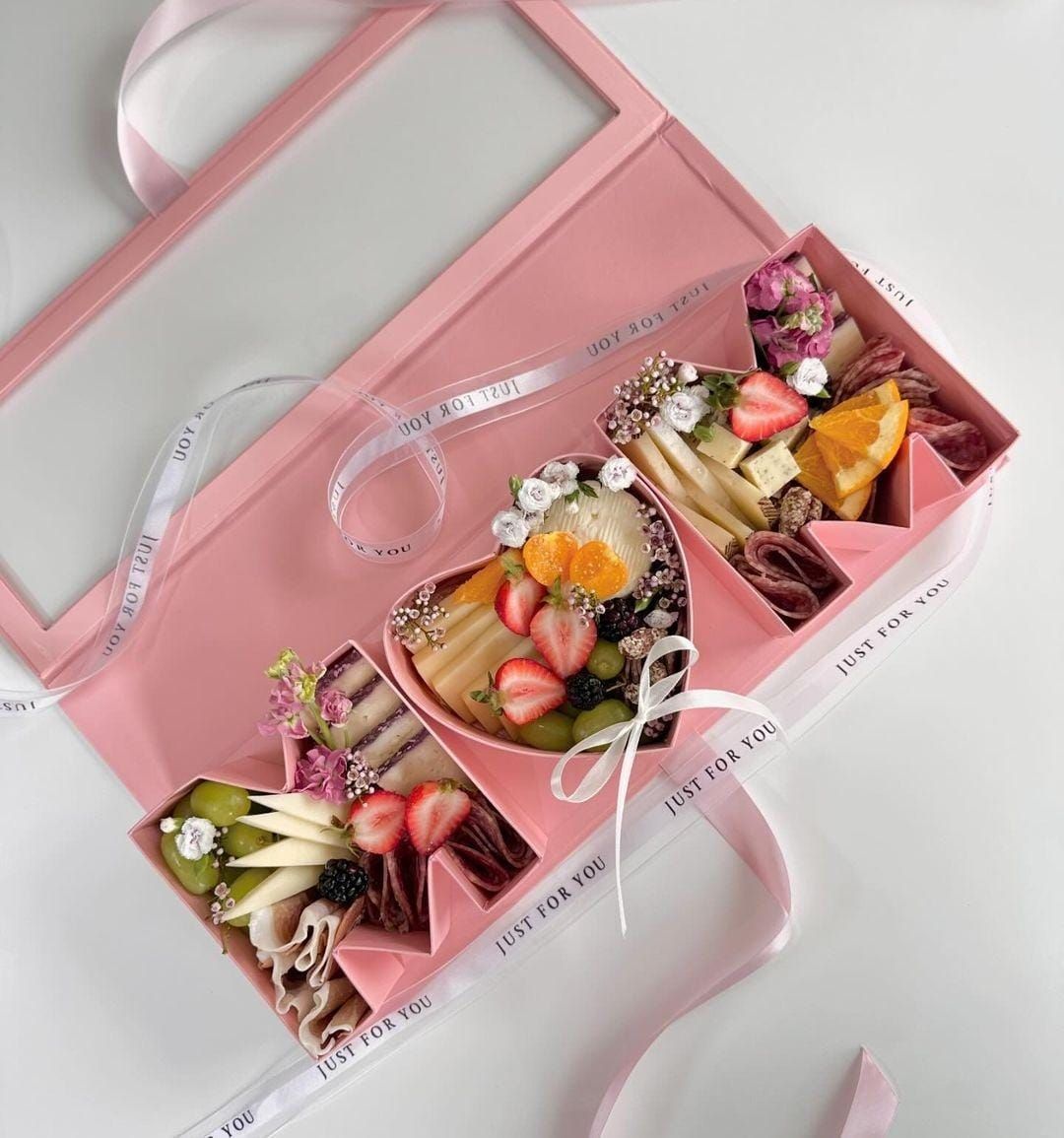 A pink box filled with fruits and flowers