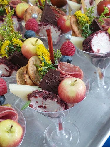 A martini glass filled with apples , strawberries , chocolate , and other fruits.