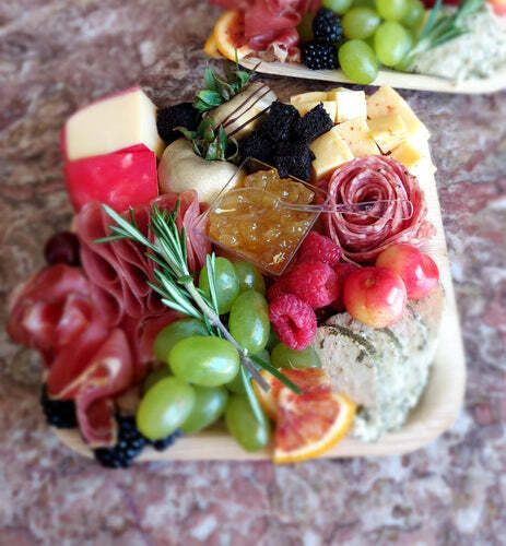 A wooden tray filled with fruits and meats on a table