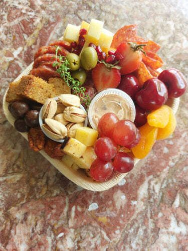 A heart shaped tray filled with fruit and nuts on a table.