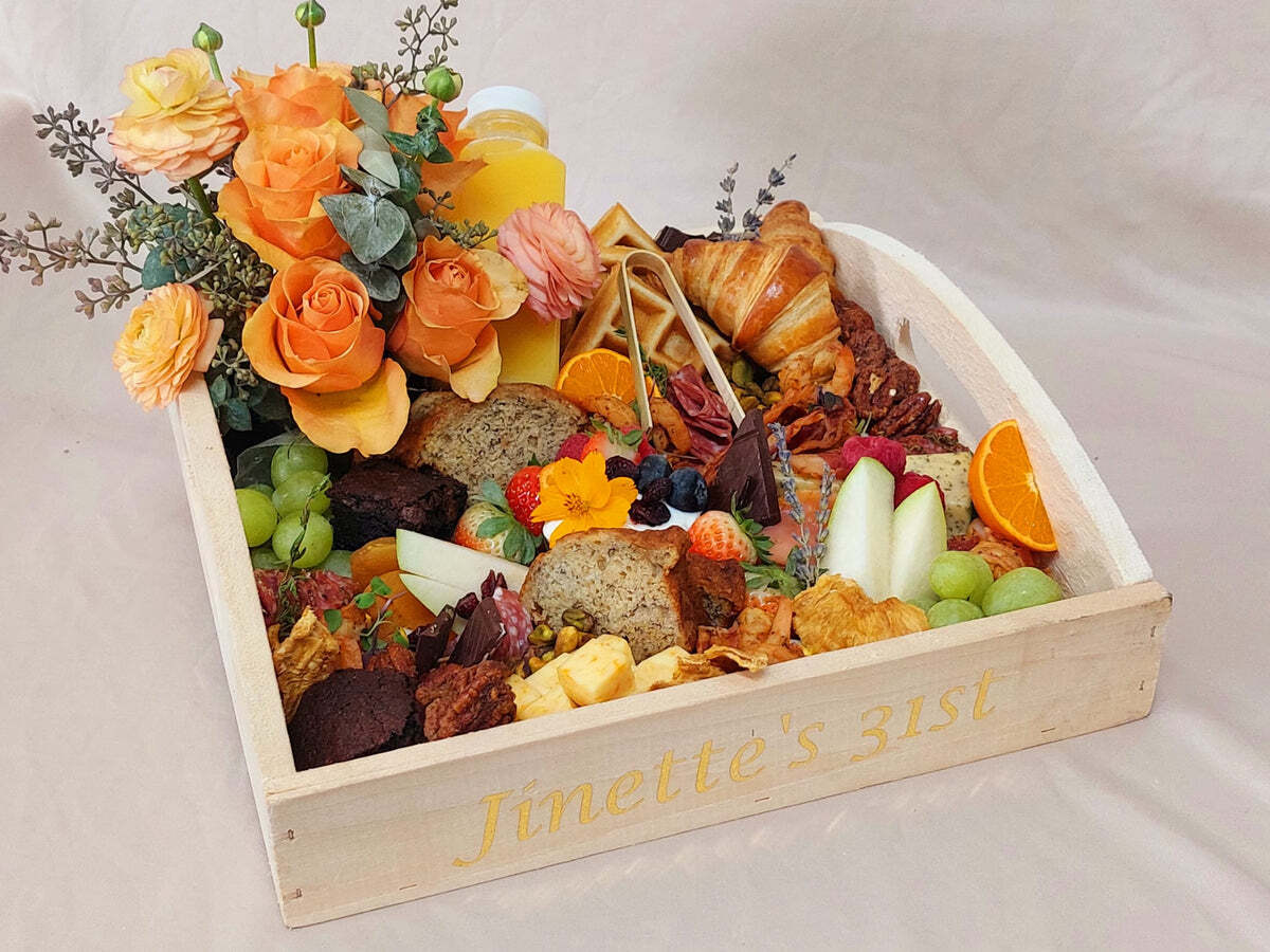 A wooden box filled with food and flowers on a table.