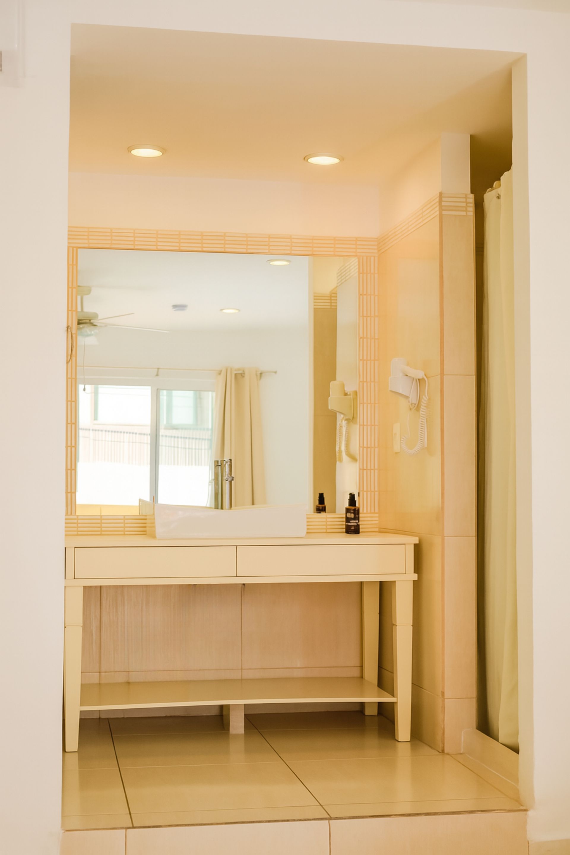 Vanity area in a bright room, with a large mirror, drawers, and shelves.