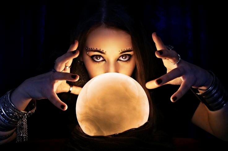 Een vrouw houdt een kristallen bol voor haar gezicht.