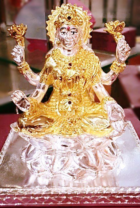 Een gouden en zilveren beeld van een vrouw zittend op een lotusbloem.