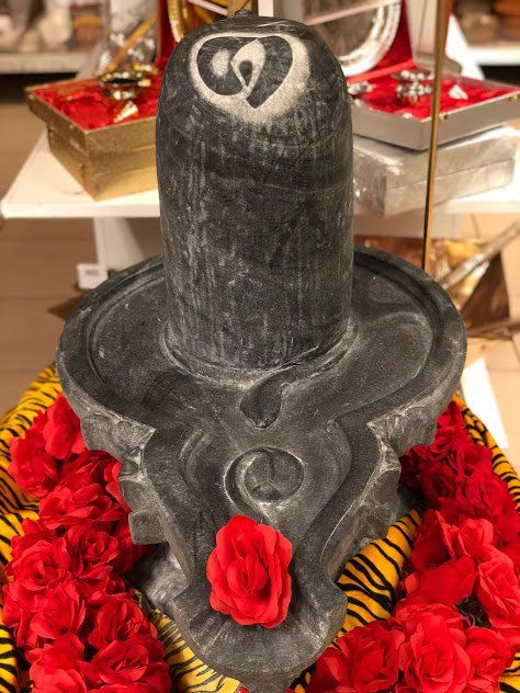 Een zwart beeld met een hart erop, omgeven door rode bloemen.