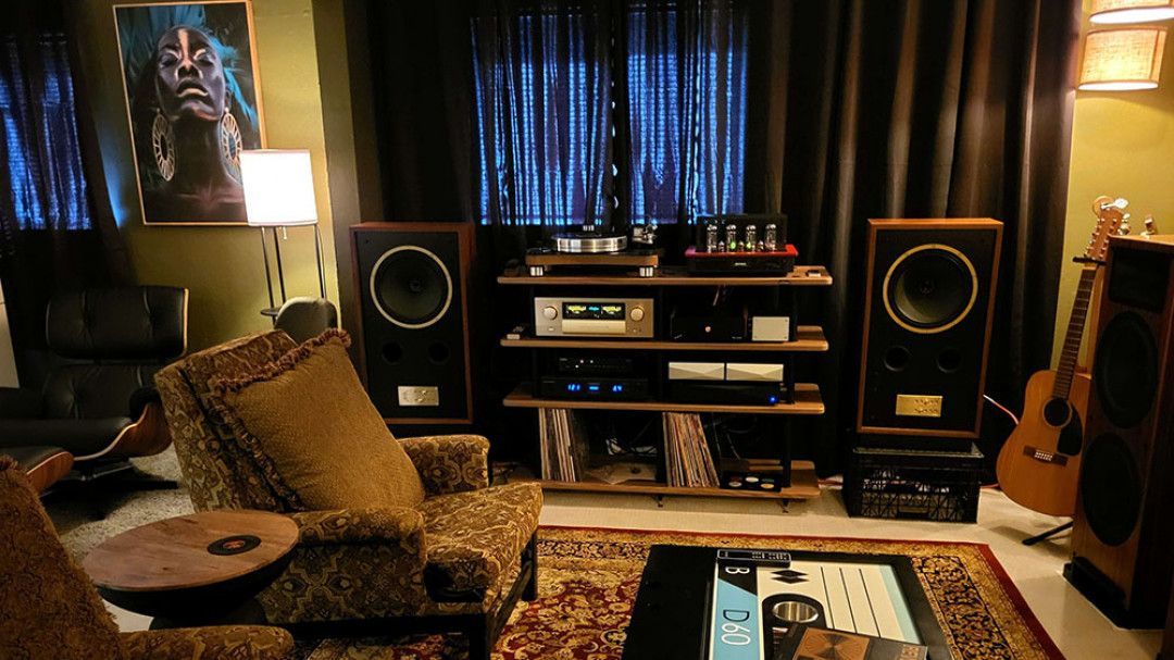 A living room with a lot of speakers and a guitar