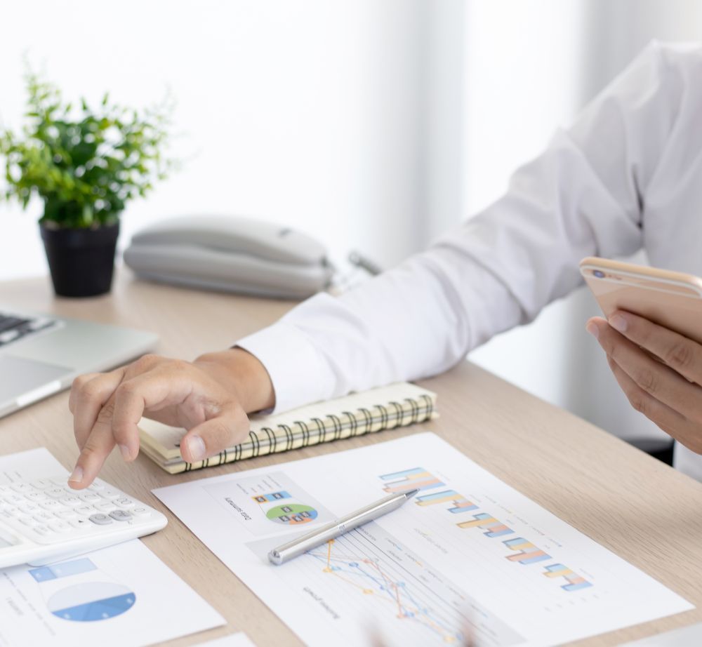 Un hombre está sentado en un escritorio con un teléfono celular y un cuaderno.