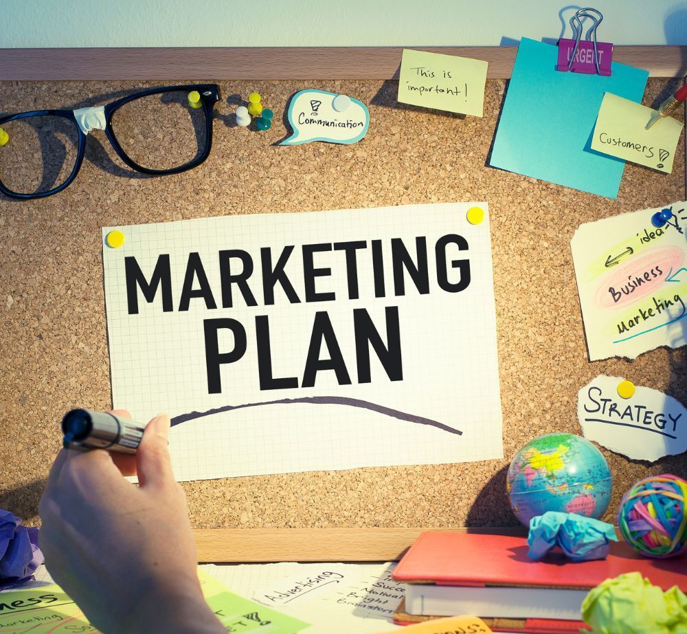 Una persona está escribiendo un plan de marketing en un tablero de corcho.