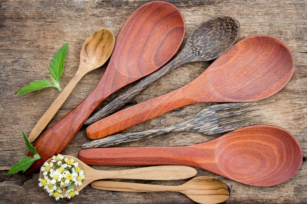A bunch of wooden spoons are sitting on a wooden table.