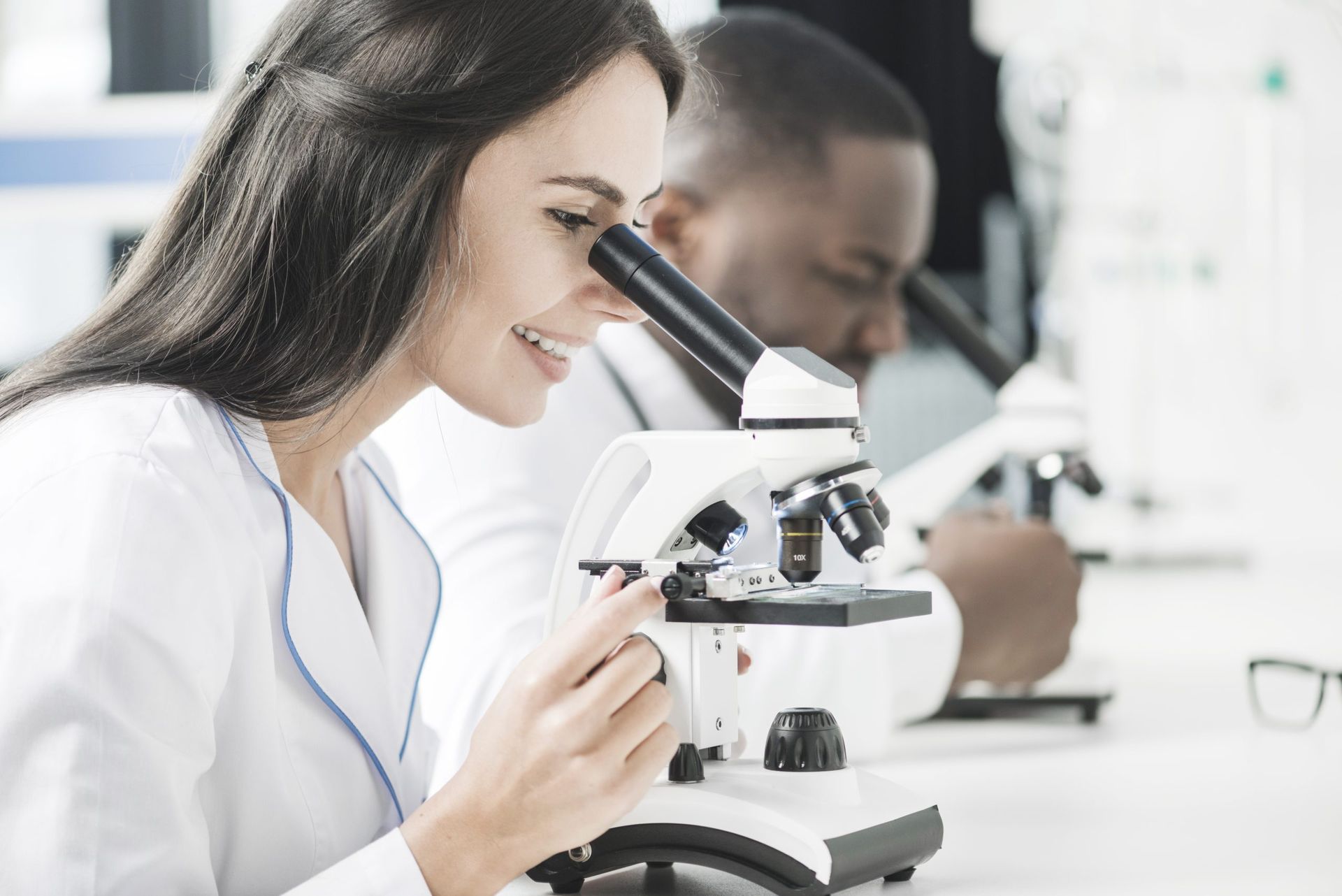 A woman is looking through a microscope in a laboratory.
