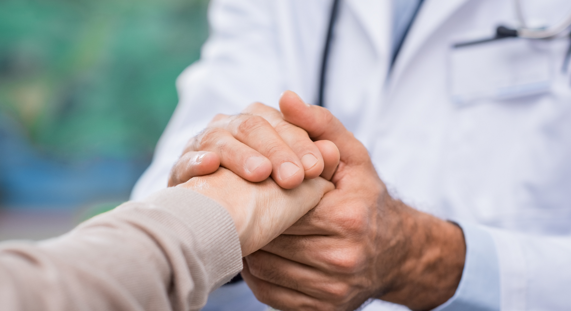 A doctor is holding the hand of a patient.