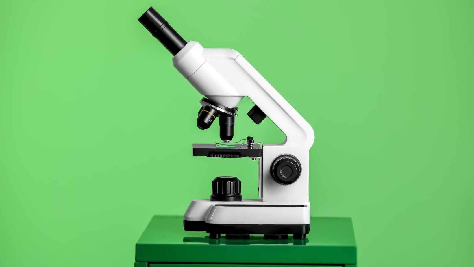 A microscope is sitting on top of a green table.