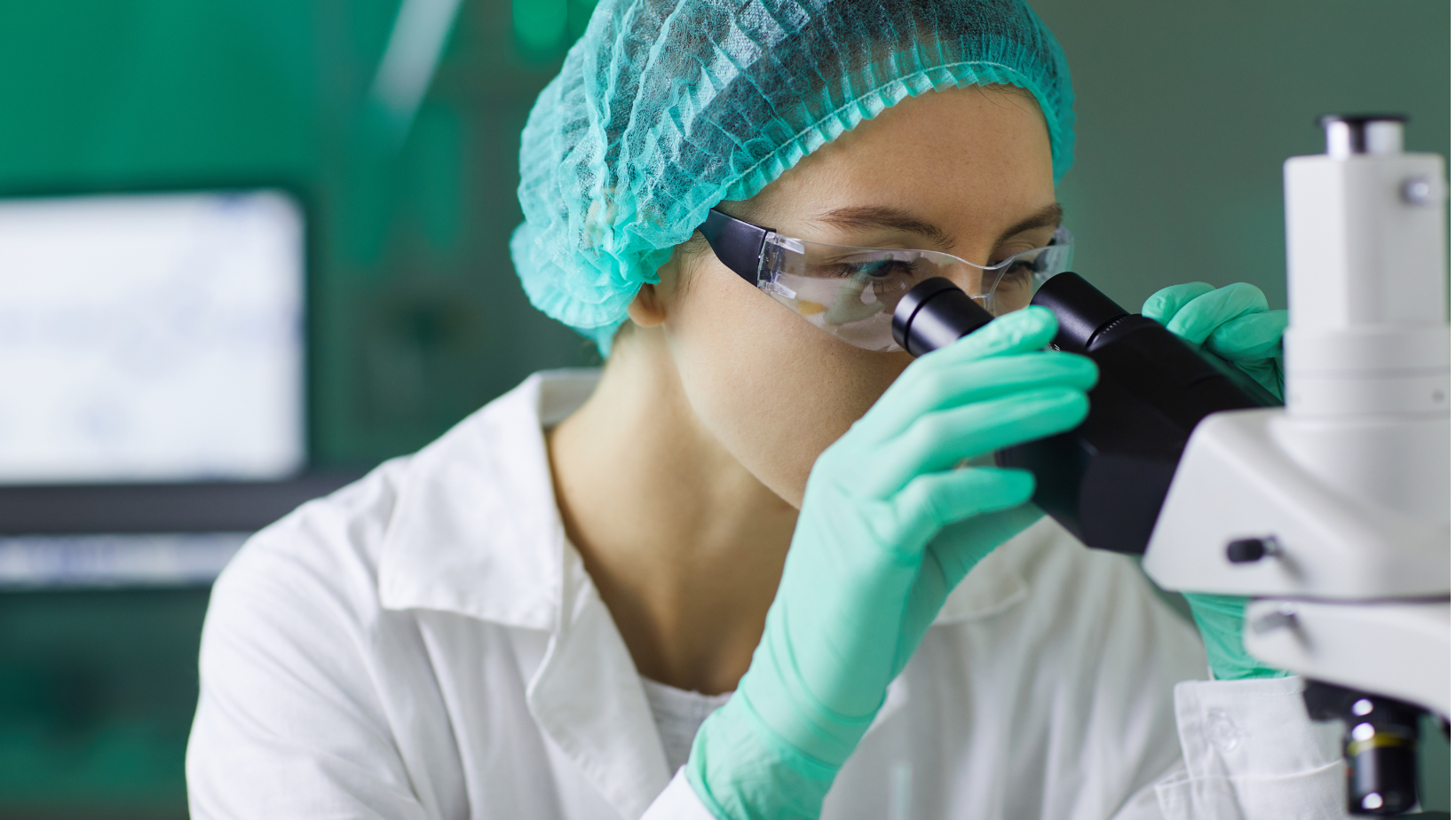 A female scientist is looking through a microscope in a laboratory.