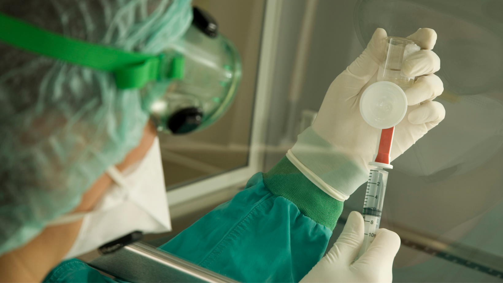 A surgeon is preparing a syringe in a laboratory.