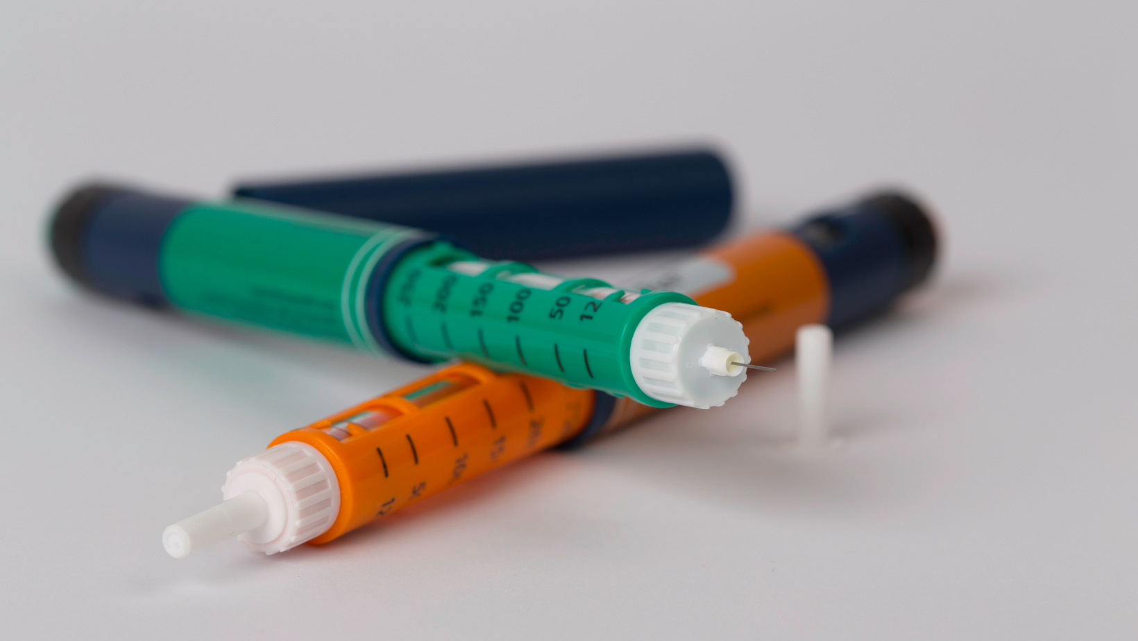 Three insulin pens are sitting next to each other on a white surface.