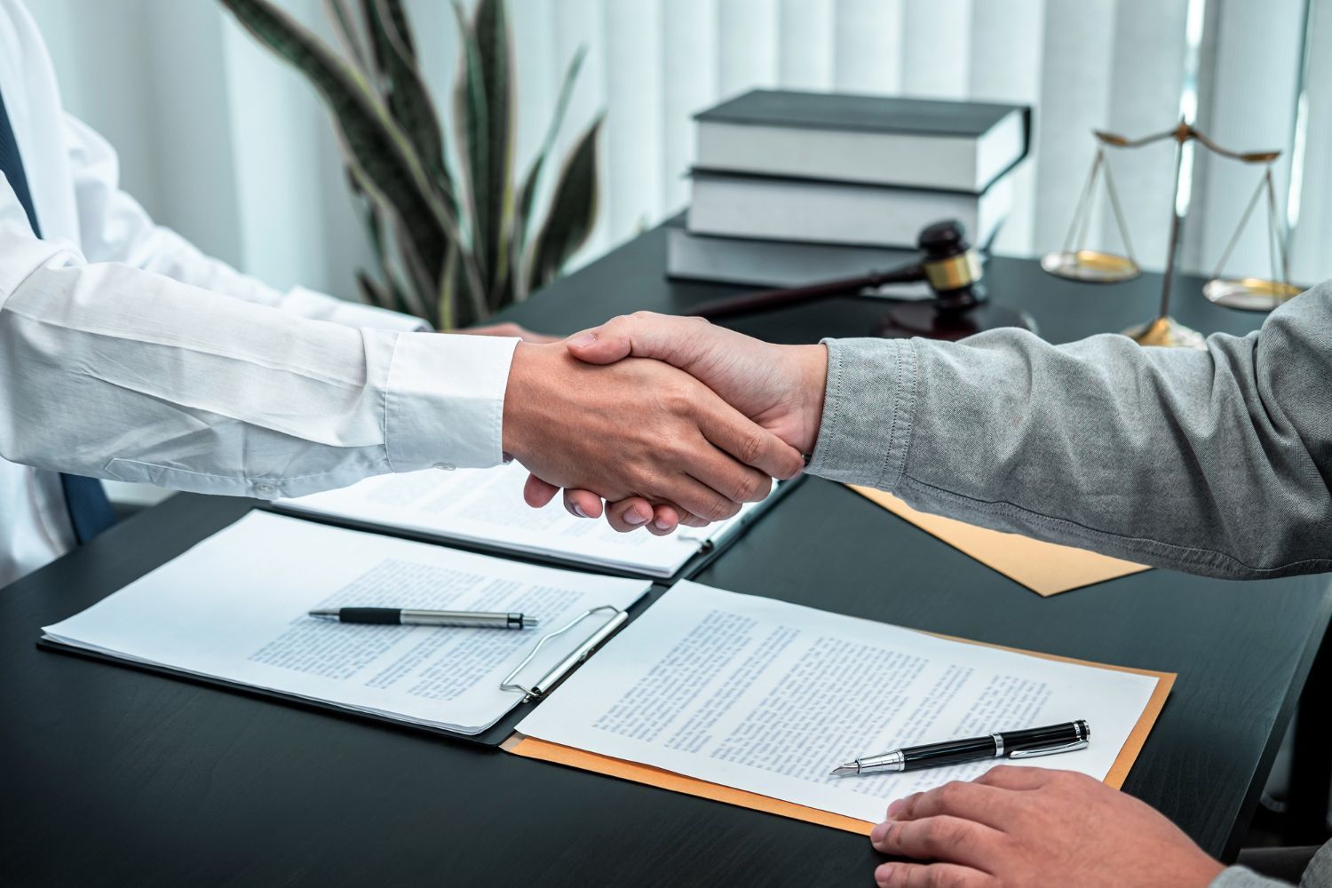 A man is shaking hands with another man while sitting at a table.