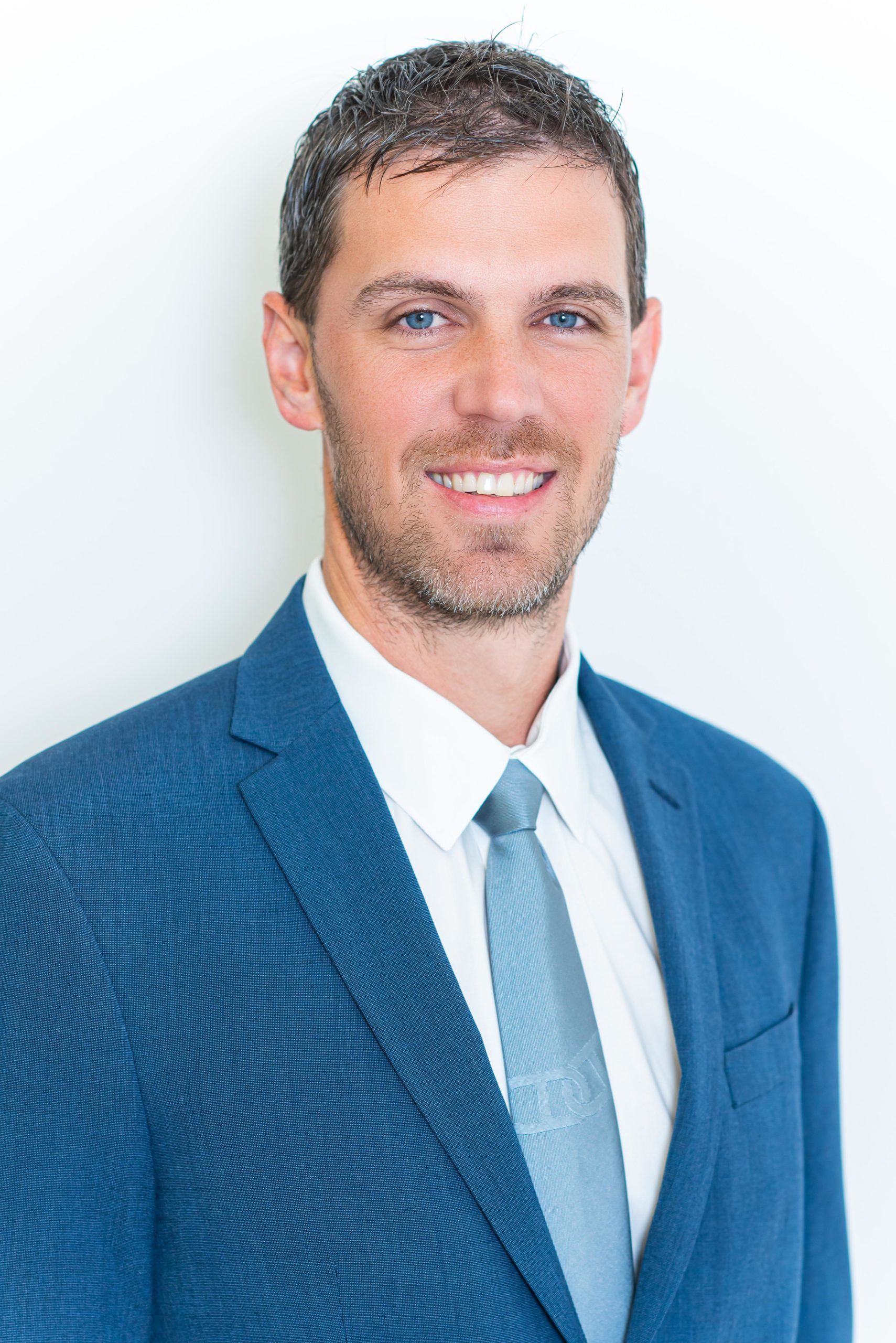 A man in a suit and tie is smiling for the camera.