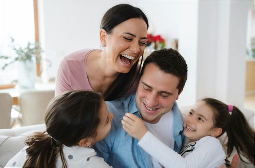 A family is sitting on a couch laughing together.