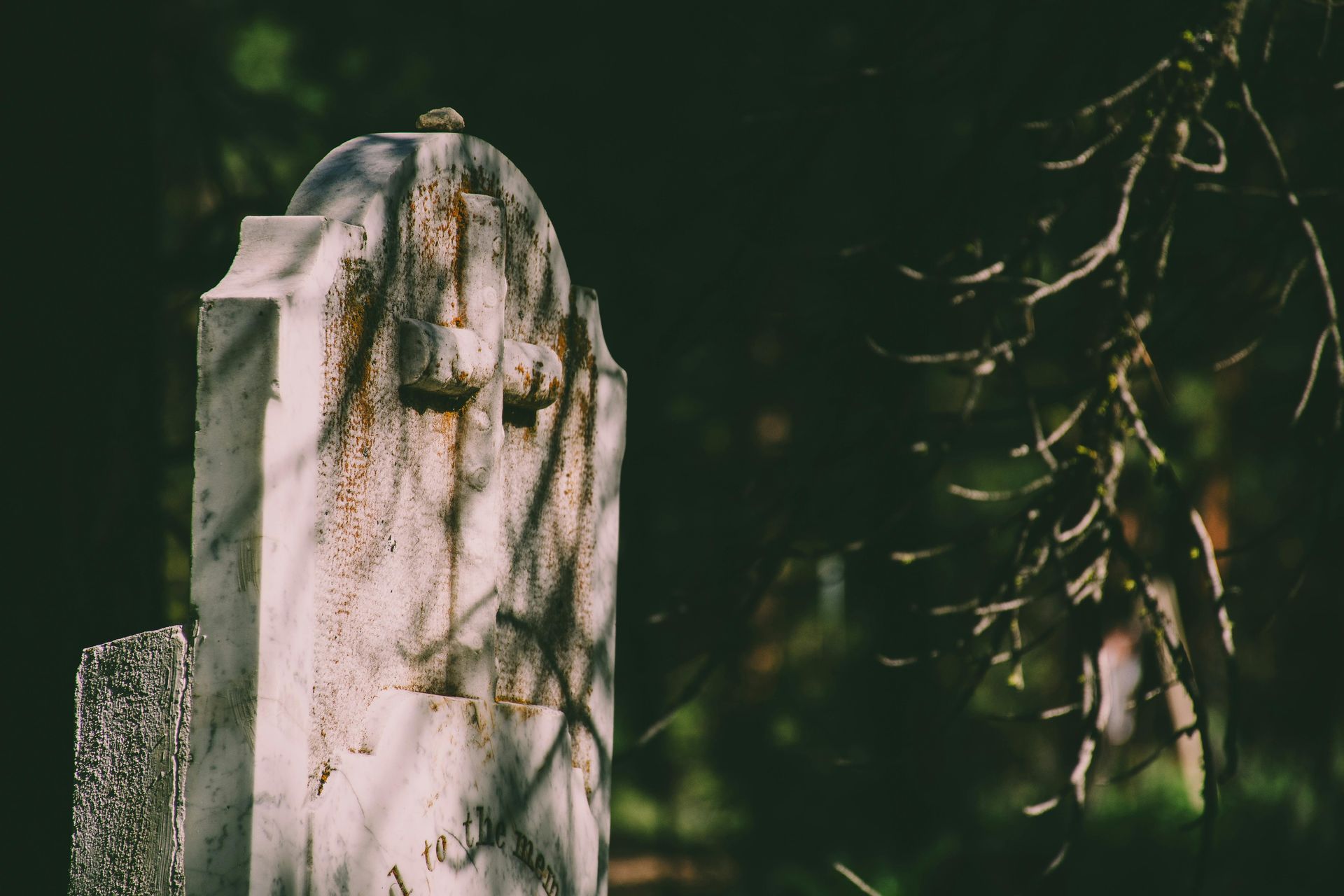 A gravestone with a cross on it in a cemetery.