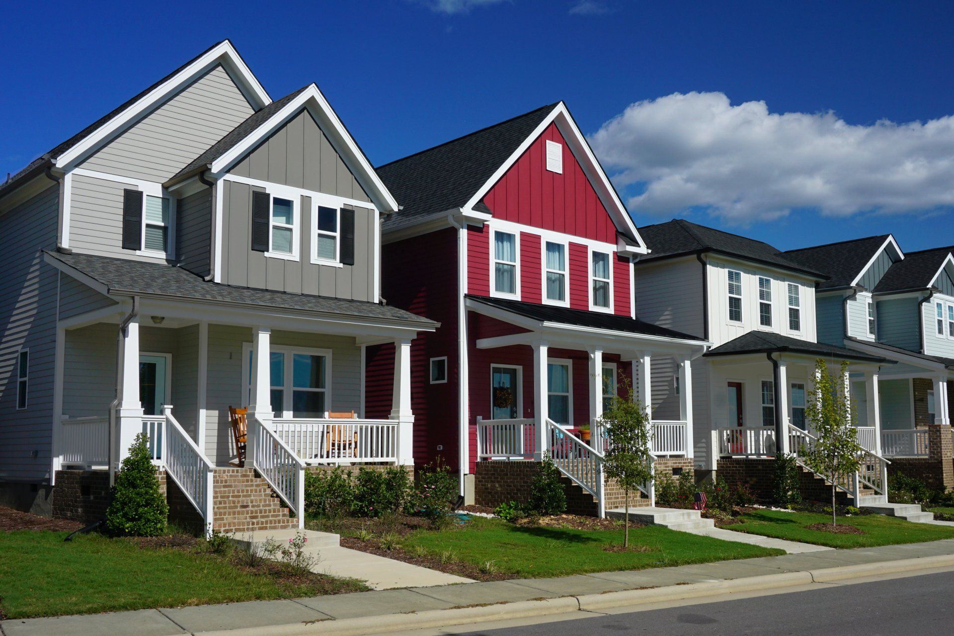 Row of colorful suburban houses with front porches along a quiet street