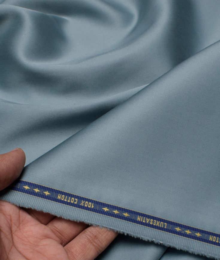 A person is holding a piece of blue satin fabric