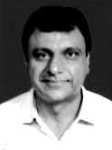 A man in a white shirt is smiling in a black and white photo.