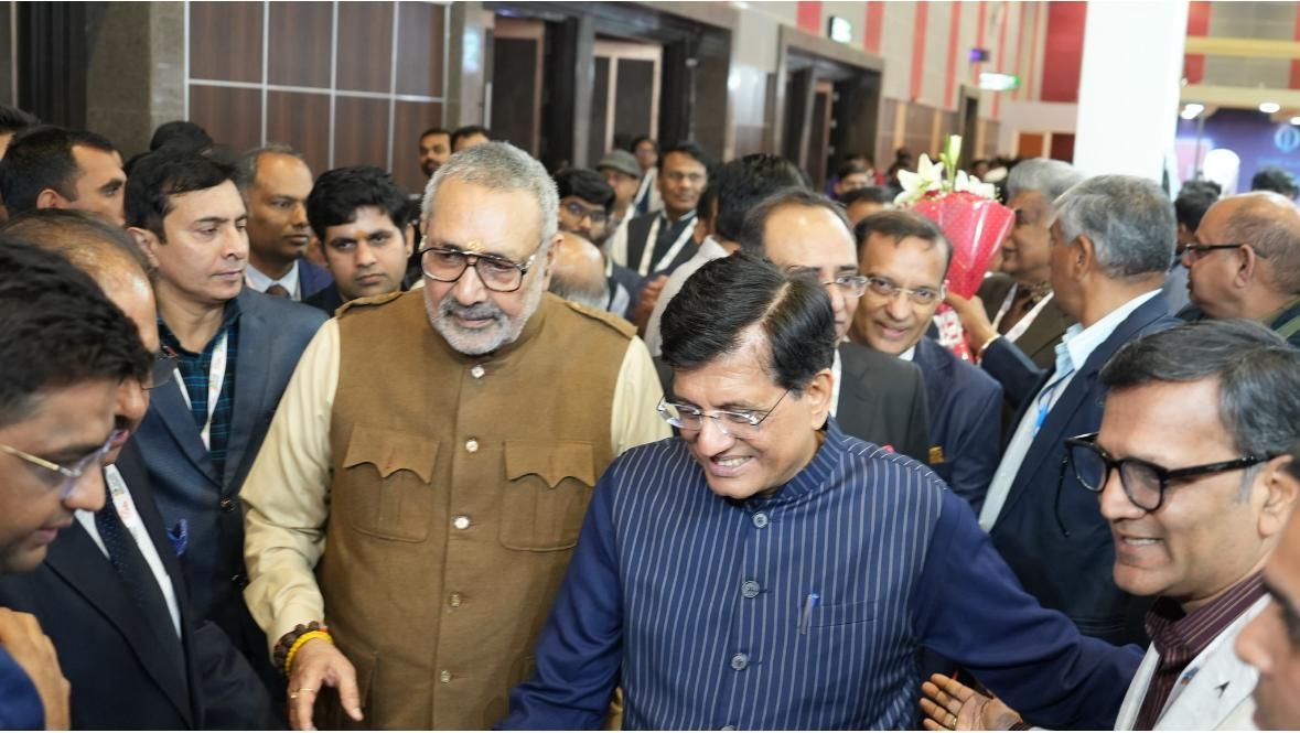 A group of men are standing in a room talking to each other.