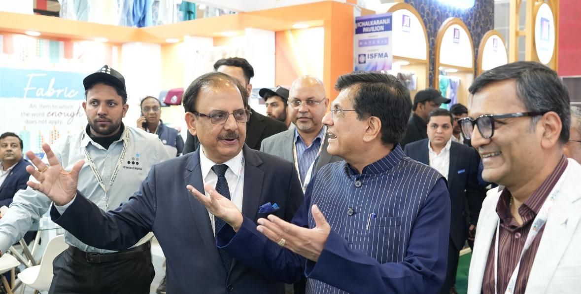 A group of men are standing in a room talking to each other.