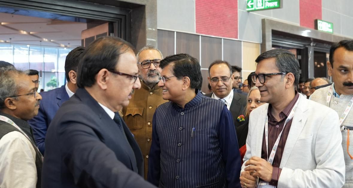 A group of men are standing in a room talking to each other.