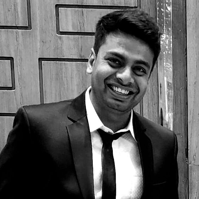 A man in a suit and tie is smiling in a black and white photo.