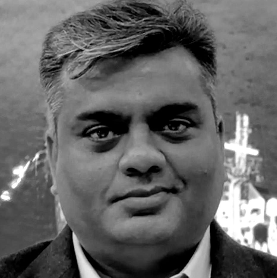 A man in a suit and tie is looking at the camera in a black and white photo.
