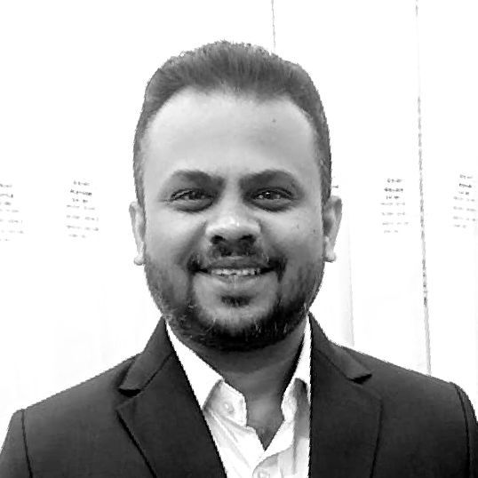 A man with a beard is wearing a suit and smiling in a black and white photo.