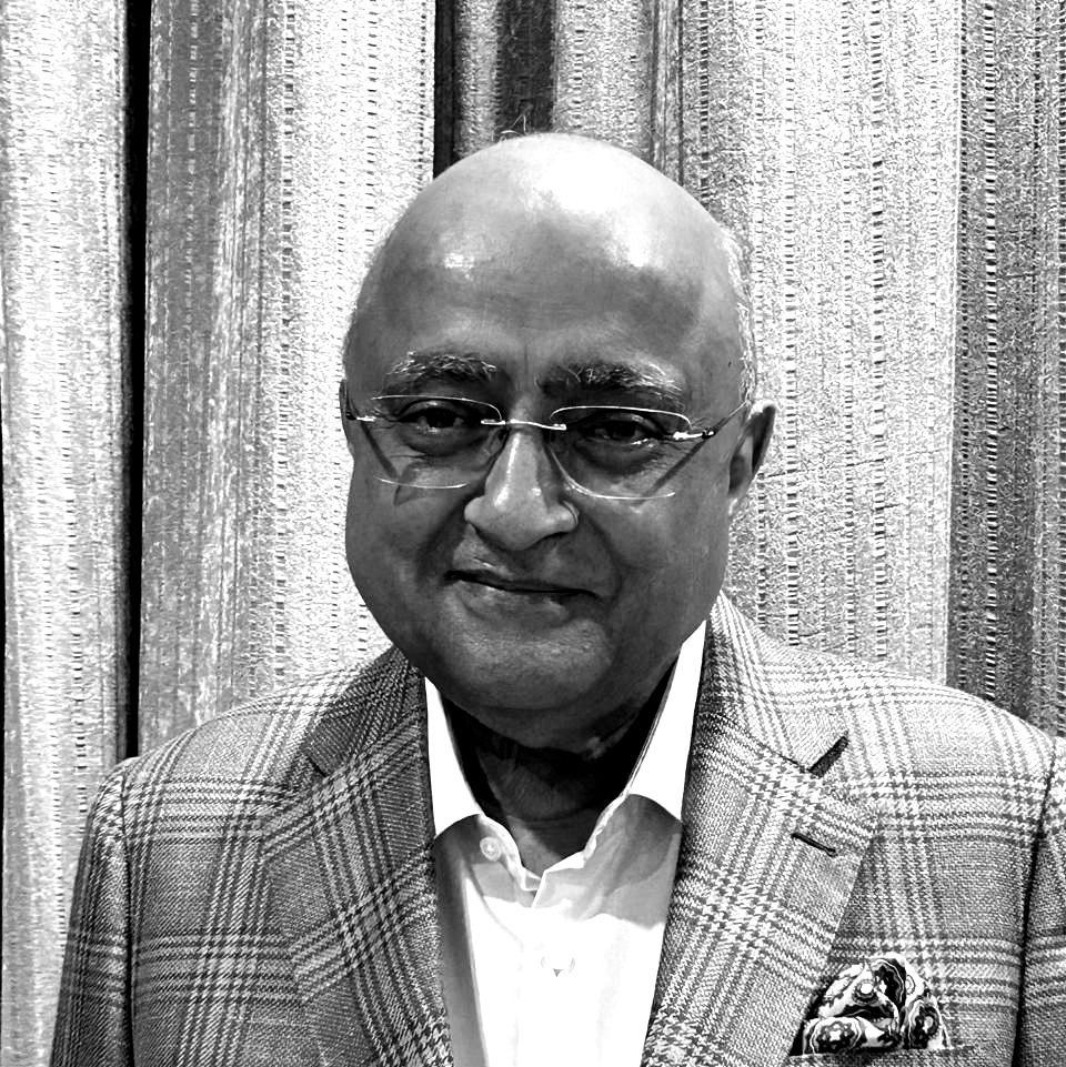A black and white photo of a bald man wearing glasses and a suit.