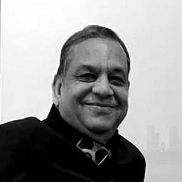 A man in a black shirt and tie is smiling in a black and white photo.