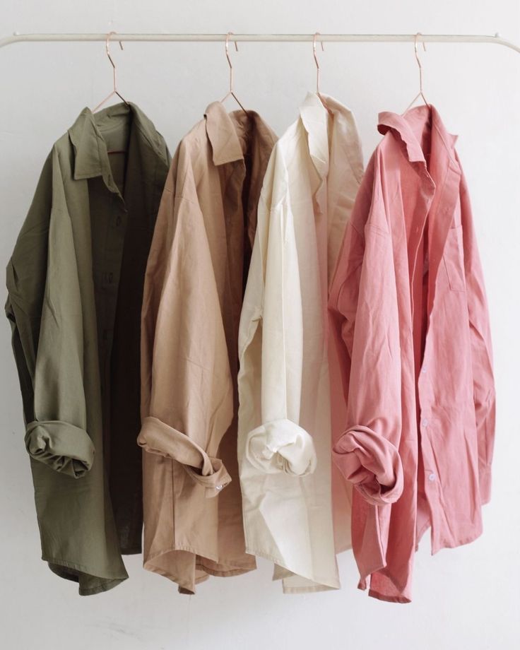 Four different colored shirts are hanging on a rack.