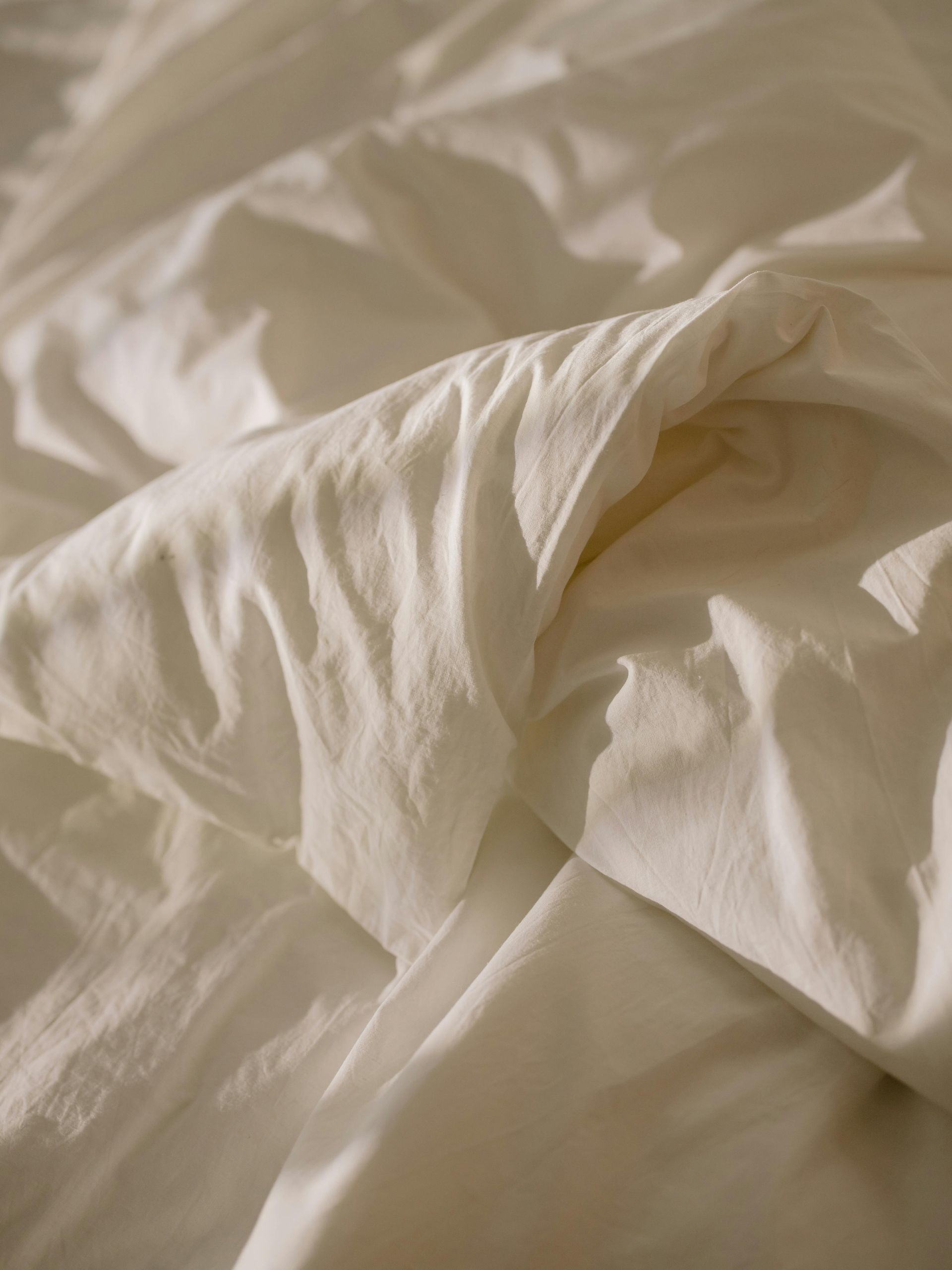 A close up of a white blanket on a bed.
