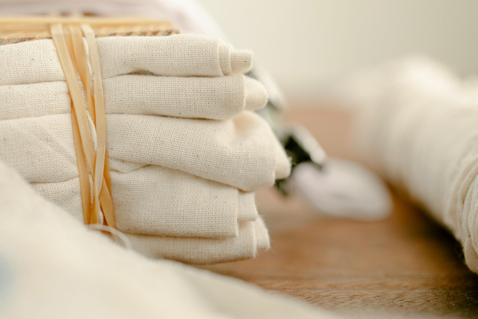 A stack of white towels tied with a rubber band on a wooden table.