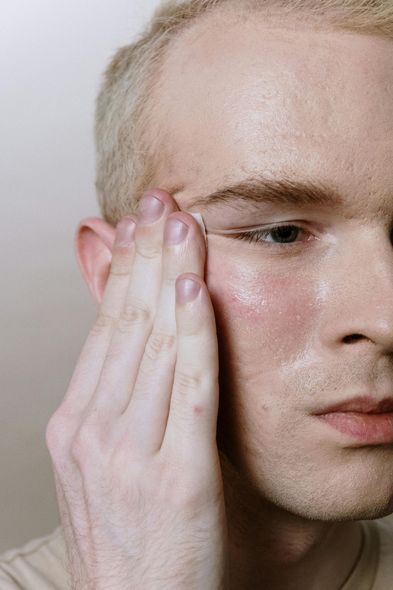 A close up of a man applying makeup to his face.