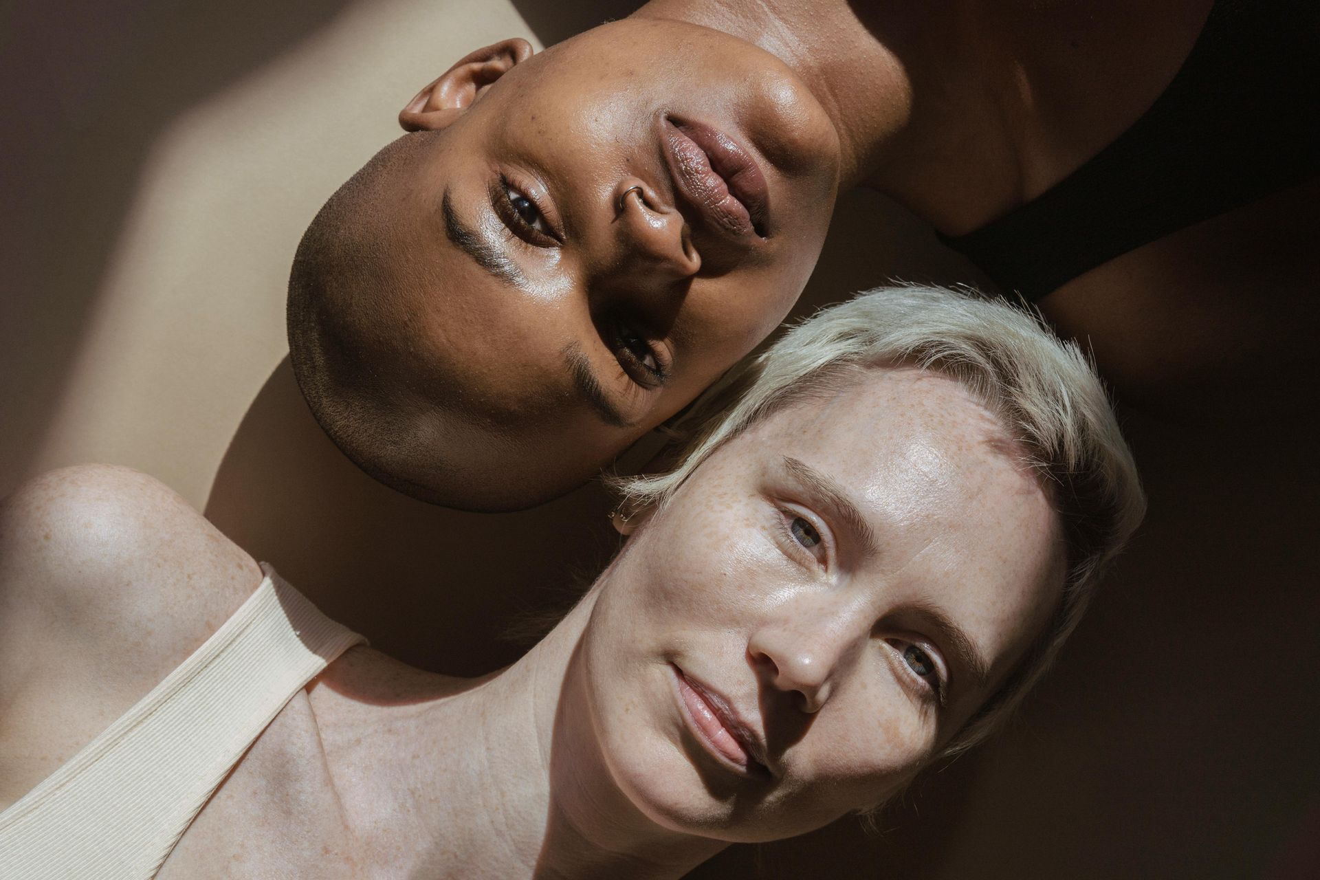 Two women are laying next to each other and looking at the camera.